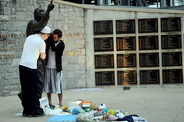 Penn State seniors Mike Elliot and Kevin Berkon embrace the Joe Paterno statue before being told to cross the street and clear the area shortly after 6 a.m. on Sunday, so the statue could be removed.