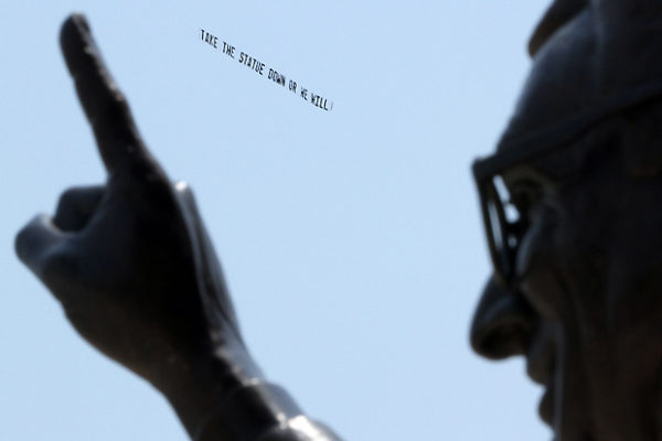 With Joe Paterno's statue in the foreground, a plane circled Penn State's Beaver Stadium towing a banner that said, "Take the statue down or we will," on July 17, 2012.