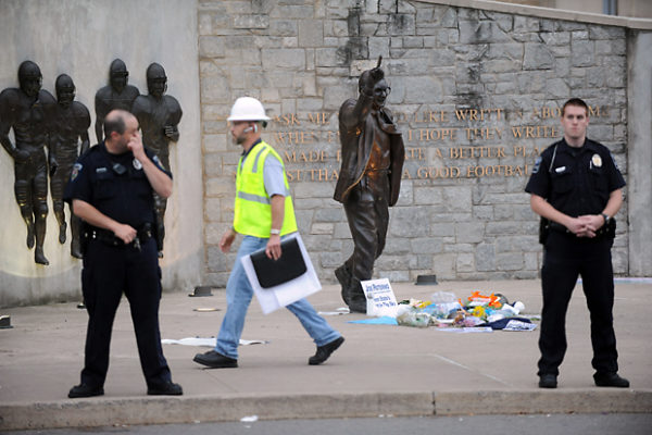 Police and construction workers surround the Joe Paterno statue before a chain-link fence was erected around the perimeter of the area in preparation to remove the monument.